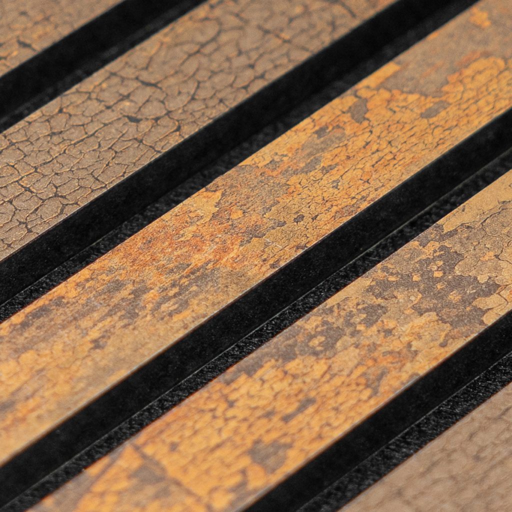 Plano detalle de panel WoodUpp: listones decorativos de madera alineados en diagonal con acabado craquelado y tonos oxidados marrones, separados por ranuras negras. Producto WoodUpp muestra textura envejecida, variaciones de color y contraste entre la madera cálida y las bandas oscuras.