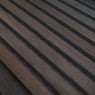 Primer plano de un panel WoodUpp formado por lamas estrechas y paralelas de madera oscura tipo roble ahumado, con vetas visibles y acabado mate; entre las lamas se aprecian ranuras negras que revelan el material aislante. Panel decorativo acústico modular de WoodUpp.