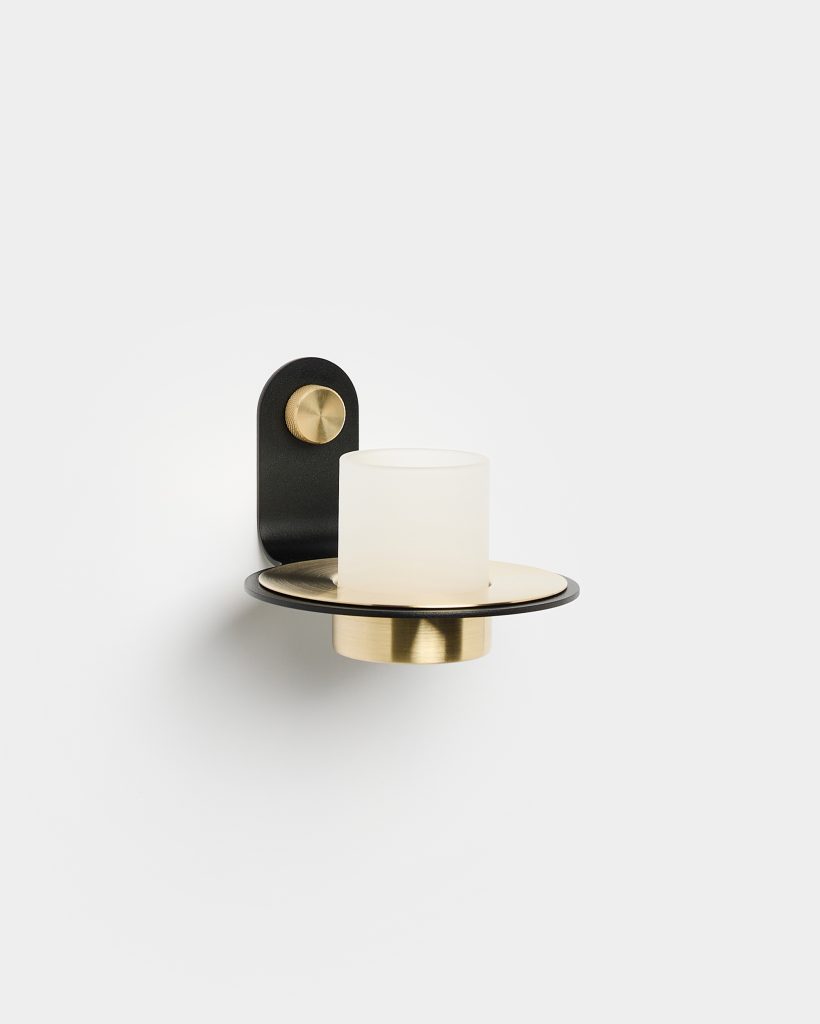 Applique de pared WoodUpp: lámpara de diseño minimalista con soporte negro curvado, botón dorado, disco y casquillo de latón cepillado y pantalla cilíndrica de cristal esmerilado blanco. Producto WoodUpp pensado para iluminación decorativa en interiores, acabado elegante y combinaciones negro-dorado.
