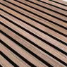 Tarima exterior WoodUpp compuesta por lamas paralelas en tonos marrón claro, con ranuras longitudinales visibles y juntas oscuras entre las tablas. Imagen en perspectiva muestra textura veteada y montaje continuo de las lamas de WoodUpp formando un pavimento exterior duradero.